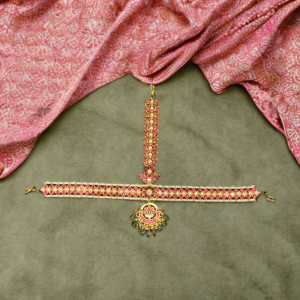 Decorative jewelry set on a green fabric background with a pink fabric draped above.
