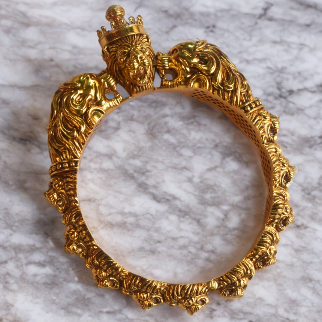 Gold bracelet with intricate designs on a marble surface