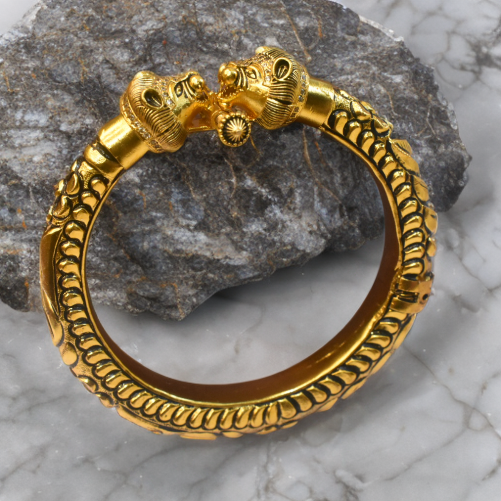 Gold bracelet with lion head design on a stone and marble background