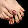 A close-up image of a woman's feet wearing gold-colored toe rings.