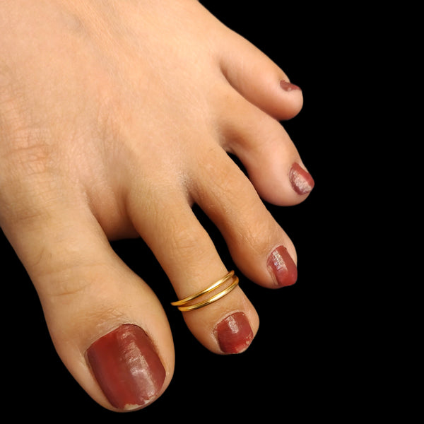 A close-up image of a woman's foot wearing a gold-colored toe ring.