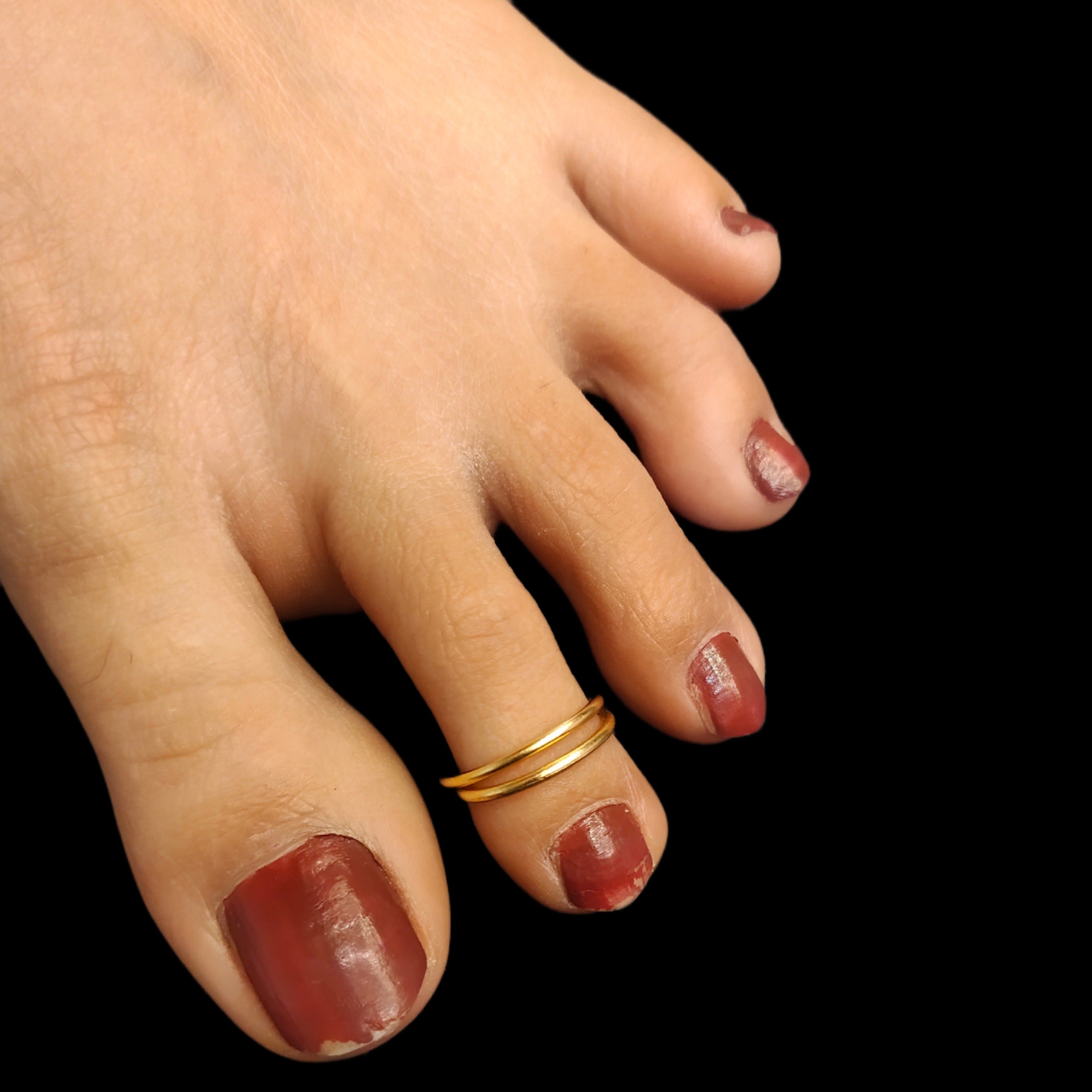 A close-up image of a woman's foot wearing a gold-colored toe ring.