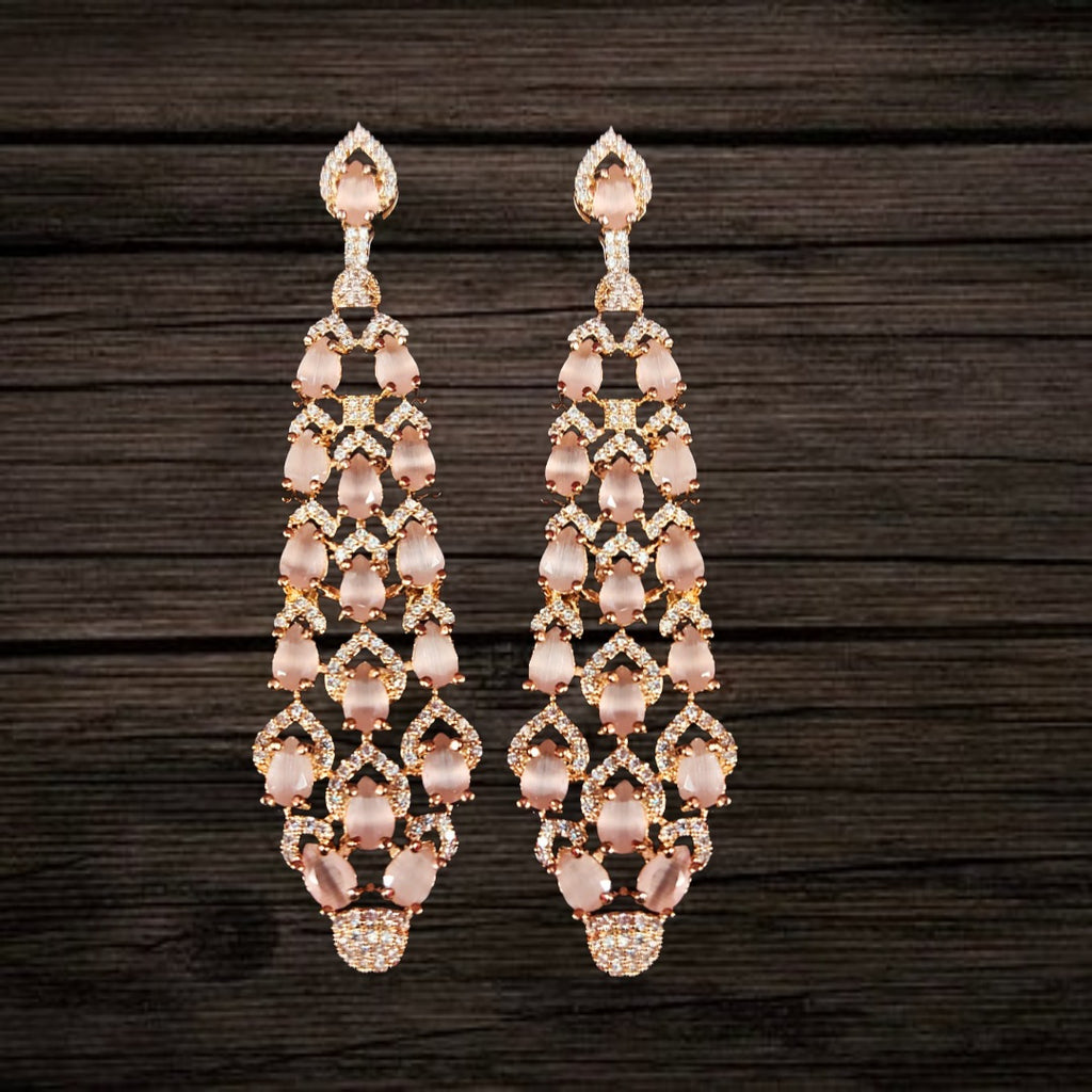 Pair of chandelier earrings with pink gemstones on a dark wooden background