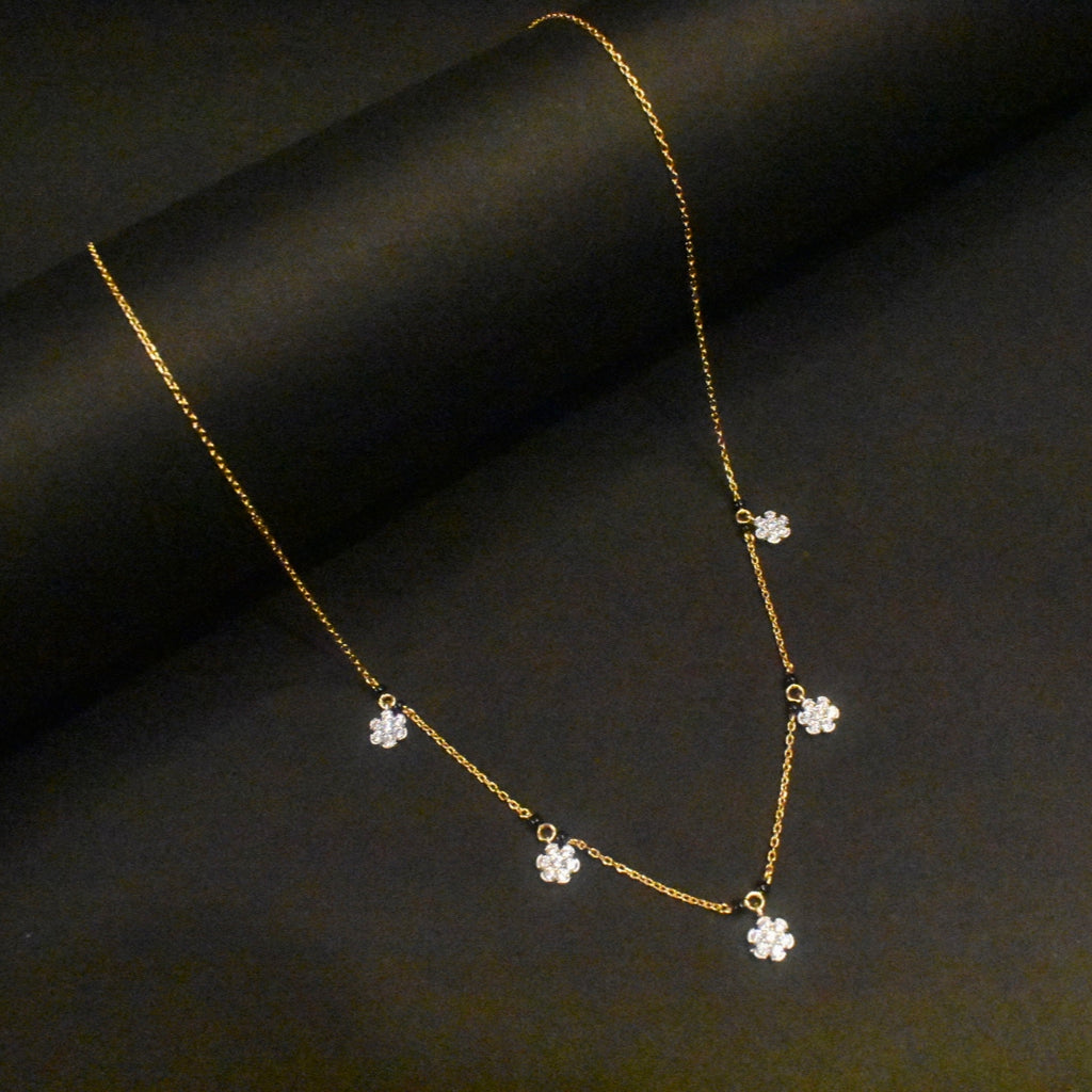 Gold necklace with flower-shaped pendants on a dark fabric background