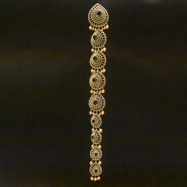 Decorative gold bracelet with green stones on a black background