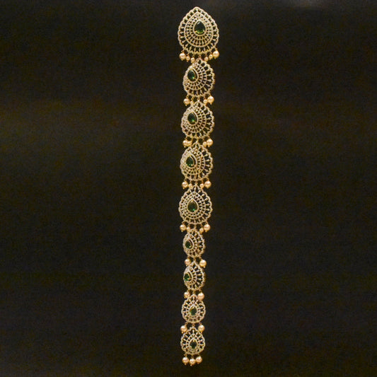 Decorative gold bracelet with green stones on a black background