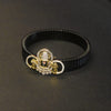 Black bracelet with a decorative gold and silver clasp on a dark background