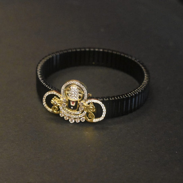 Black bracelet with a decorative gold and silver clasp on a dark background