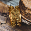 Gold bangles with intricate designs on a wooden surface