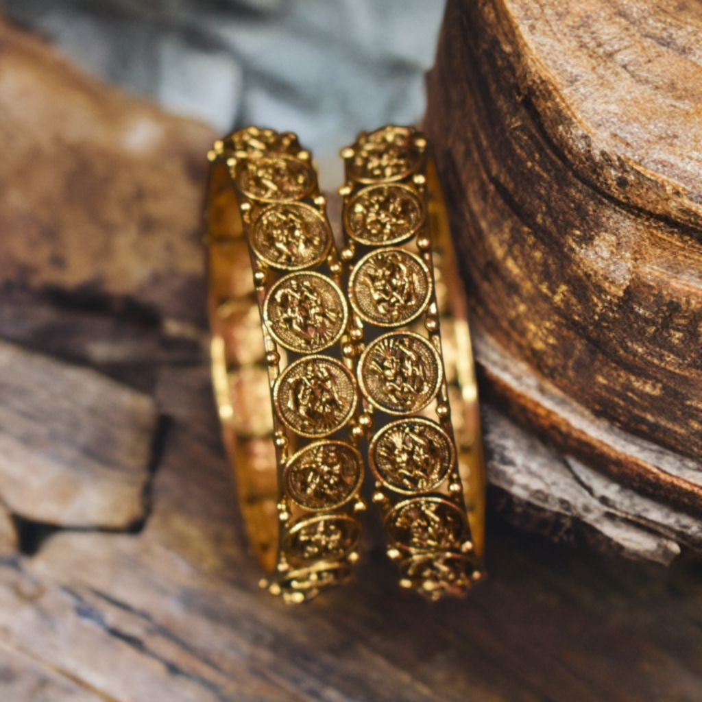 Gold bangles with intricate designs on a wooden surface