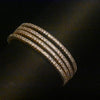 Gold bracelet with multiple rows of diamonds on a dark background