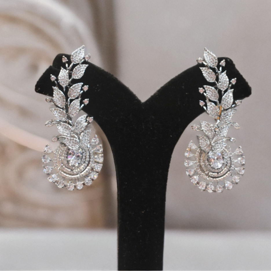 Pair of silver earrings on a black stand with a blurred background