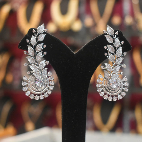 Pair of silver earrings on a black stand with a blurred background
