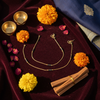 Gold plated black bead mangalsutra anklet flat lay with marigolds and cultural props