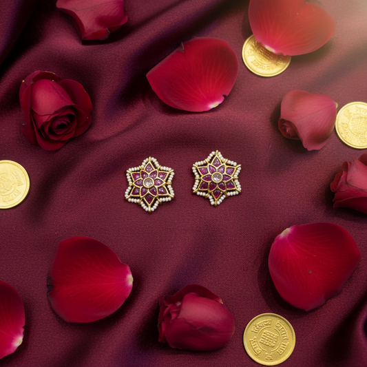 Kundan Ruby Star Stud Earrings flat lay on burgundy silk with rose petals