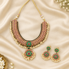 Kempu necklace and matching earrings arranged on cream silk