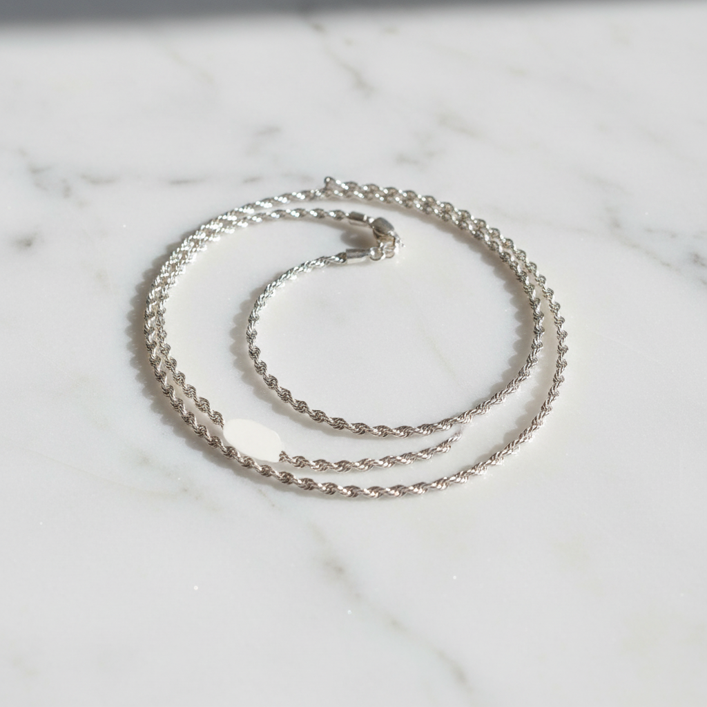 Silver rope chain necklace on marble surface
