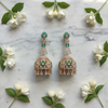Flat lay - rose gold CZ long jhumka earrings on white marble with jasmine flowers