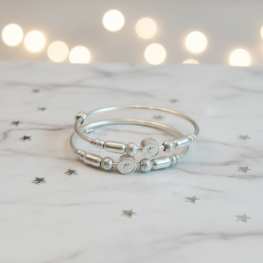 Lifestyle flat lay of silver star coin bangles for kids on marble