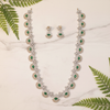 Emerald CZ necklace set lifestyle flat lay with green leaves