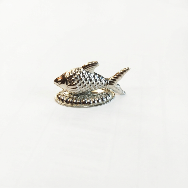 Silver fish idol with textured scales on a decorative oval base against a white background