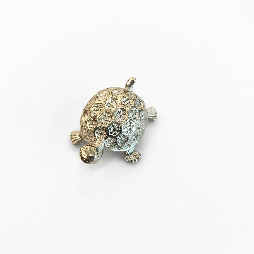 Silver turtle idol with patterned shell, angled view on white background