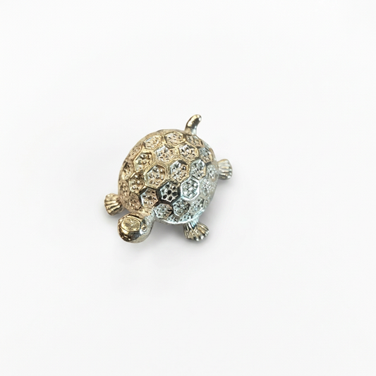 Silver turtle idol with patterned shell, angled view on white background
