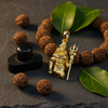 Lord Shiva gold pendant on stone surface with rudraksha and bilva leaves – devotional styling