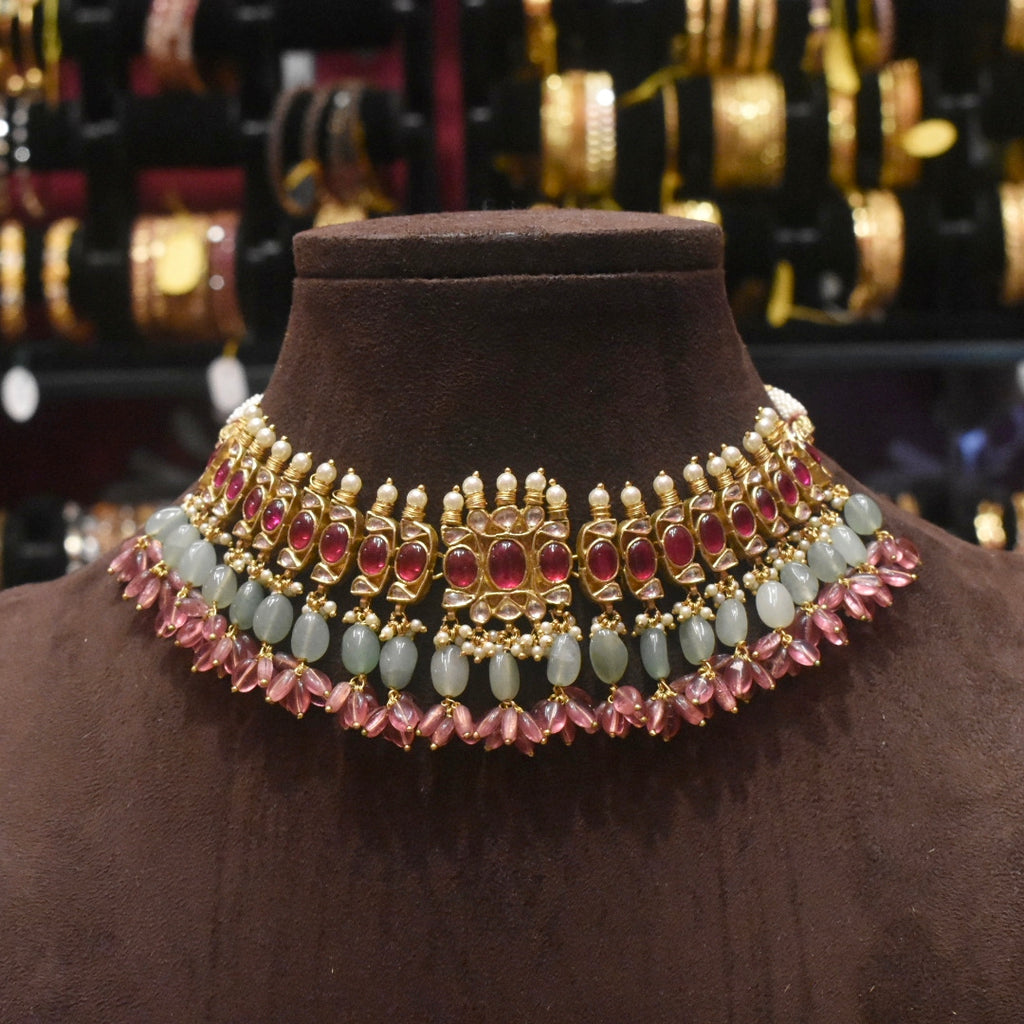 Ornate necklace with gemstones on a brown mannequin against a blurred jewelry background