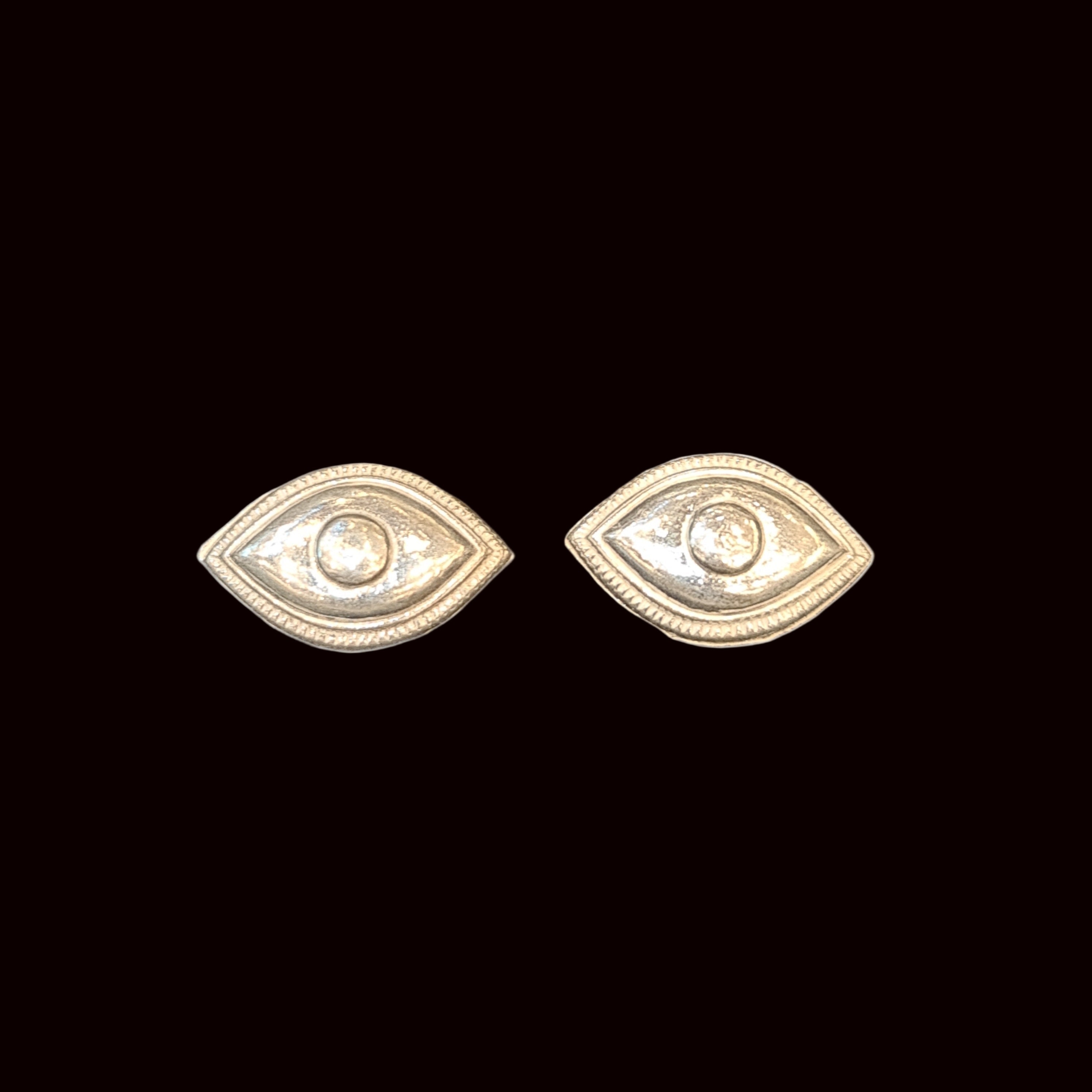 Gold eye-shaped earrings on a white background