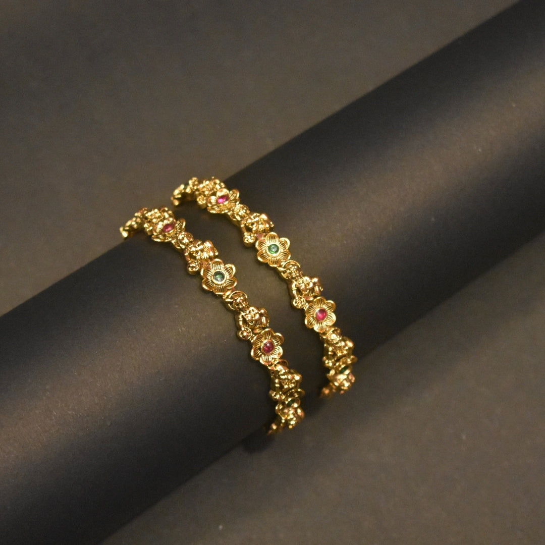 Gold bracelet with gemstones on a dark cylindrical object