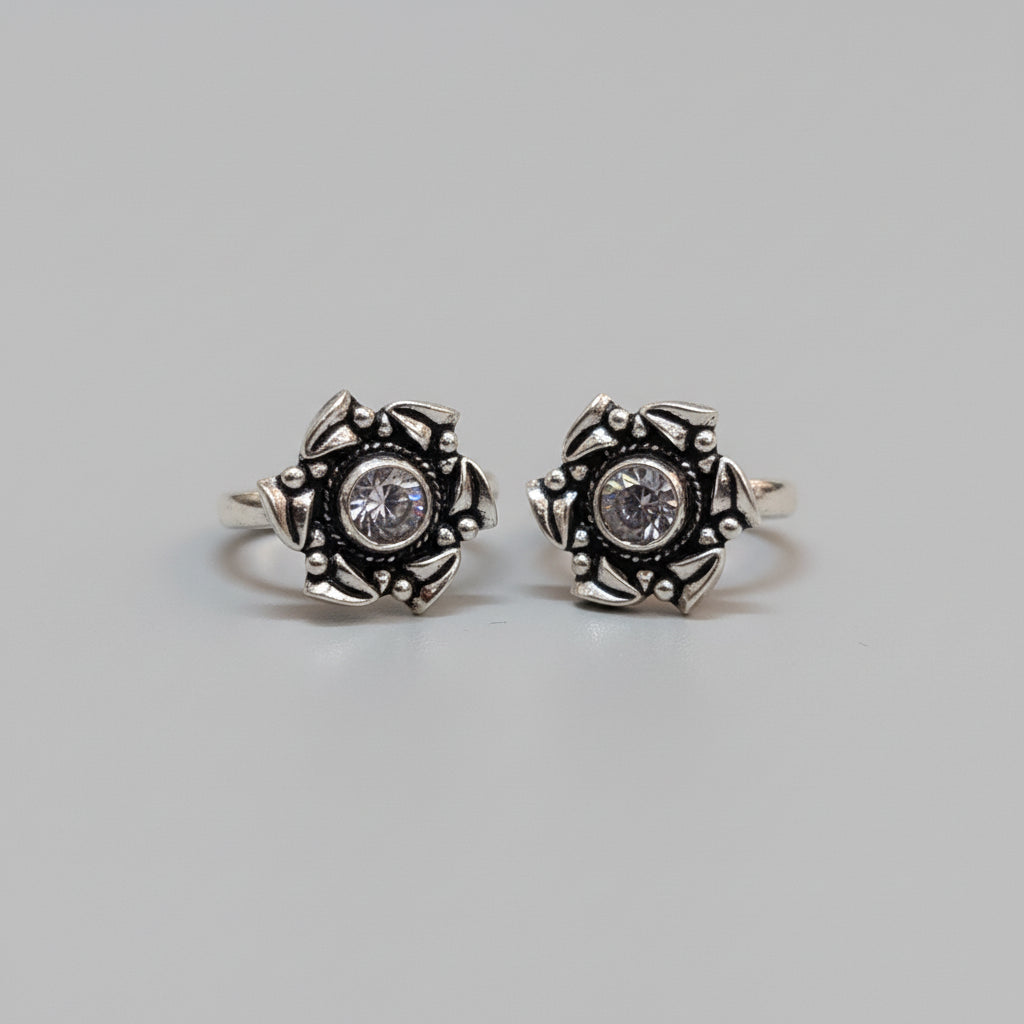 A pair of silver toe rings with ruby and emerald stones