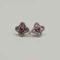 A pair of 92.5 silver toe rings with ruby and emerald embellishments, placed on a red leaf background.