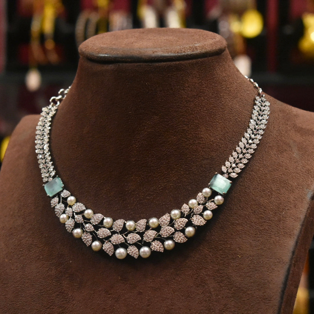 Delicate necklace with pearls and gemstones on a brown velvet stand.
