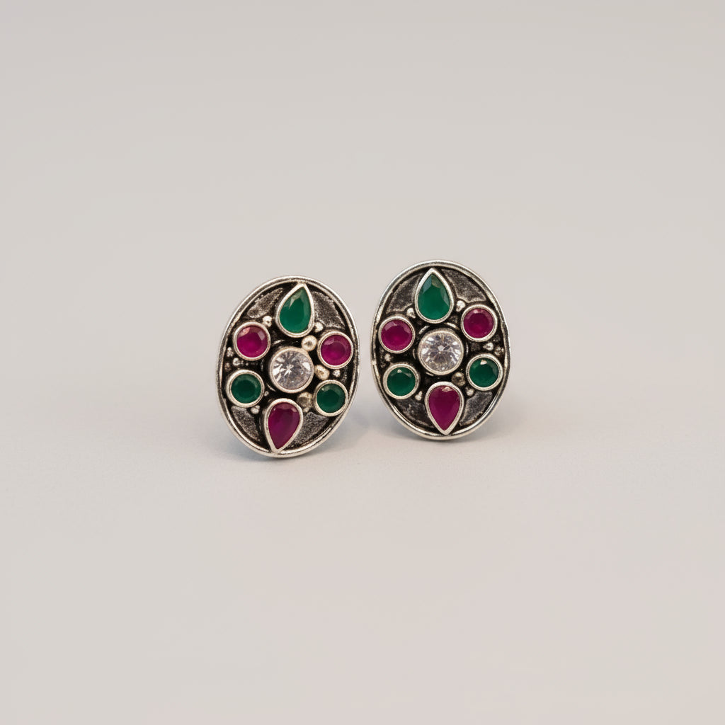 A pair of 92.5 silver toe rings with ruby and emerald embellishments, displayed on a red background with a green leaf.