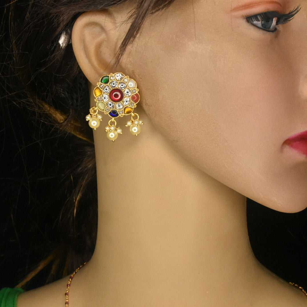 A pair of gold-colored Navratna stud earrings featuring multiple colored stones, displayed on an ear mannequin.